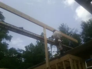 Carpenter setting a ridge beam over a new addition frame — Ice Dam Removal by Roofing Brothers in New Waverly