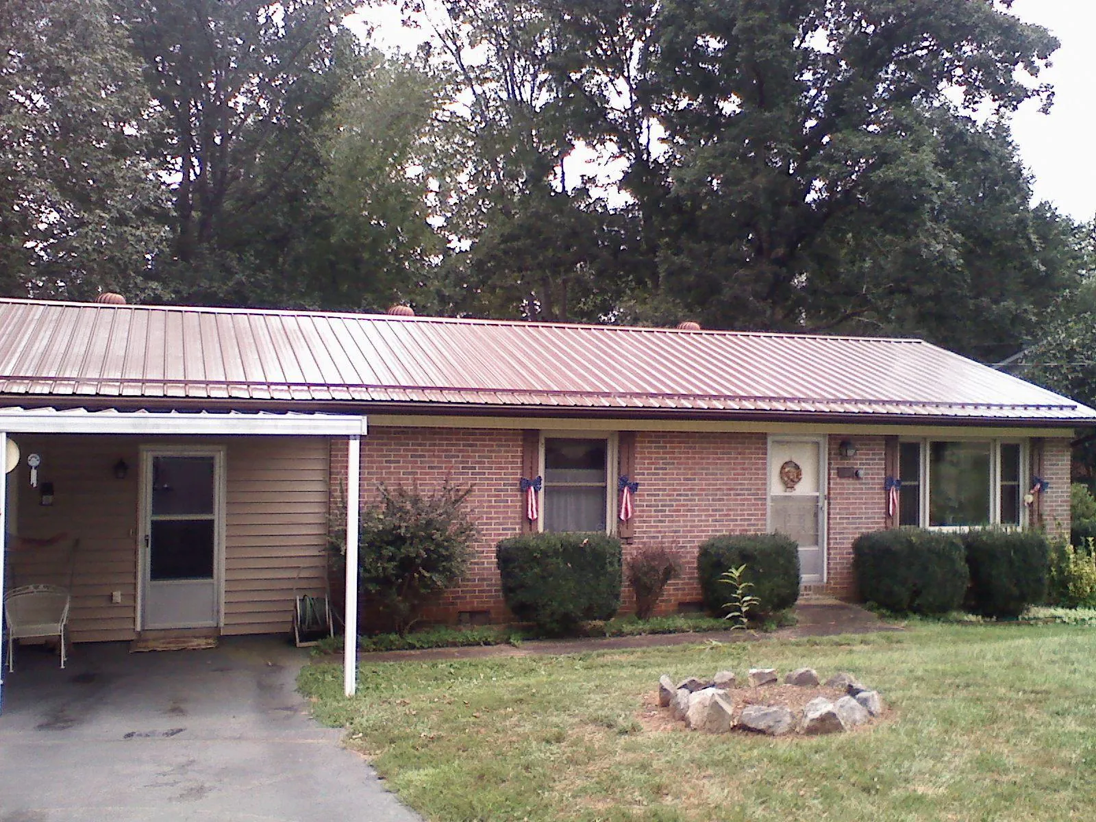 Bronze metal roof and carport on a brick ranch home — Roof Repair work by our crew in New Waverly